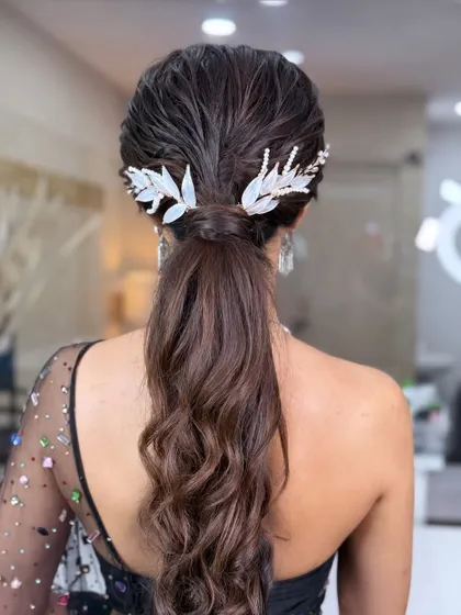 A sleek and stylish wet-look ponytail. This high-fashion style is perfect for a cocktail party or reception, adorned with elegant leafy accessories.