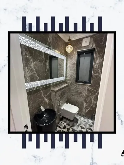 This powder room makes a bold statement with a black vessel sink, dark marble walls, and a unique geometric floor pattern.