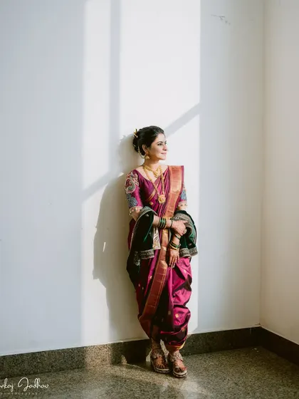 A stunning portrait of the bride, Shruti, standing in a patch of sunlight, which beautifully illuminates her traditional Nauvari saree.
