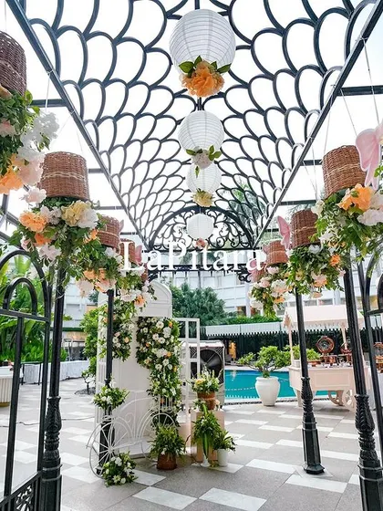A stunning poolside walkway with a decorative iron trellis, adorned with hanging baskets of flowers for the high-tea party.