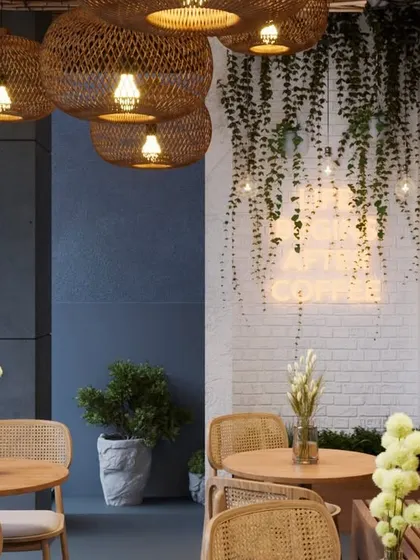 A closer look at the details that create the ambiance. The cascading vines on the white brick wall, paired with the warm glow of the neon sign and woven light fixtures, create a perfect corner that is both rustic and modern.