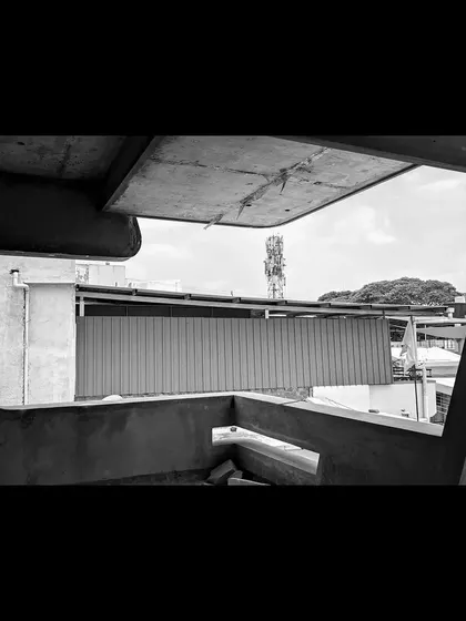 An abstract, framed view from within a structure under construction, focusing on the unique shapes and curves of the concrete work.