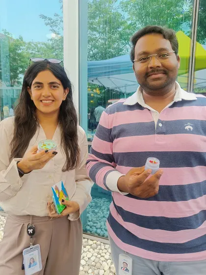 Two colleagues proudly display their finished candles, a fun souvenir from their company's event.