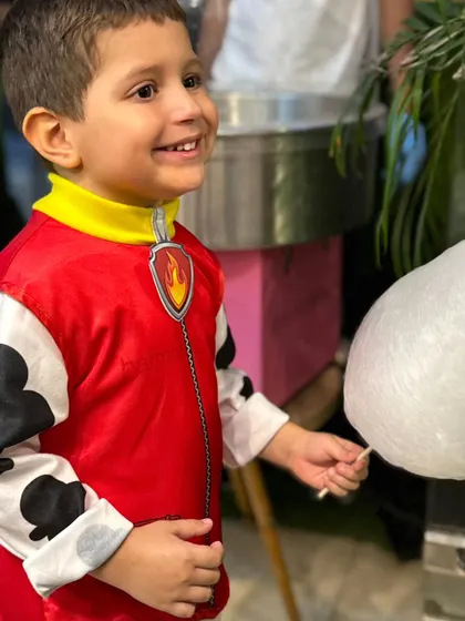 A huge smile from a happy boy in his costume, holding a freshly made stick of candy floss. It's a classic party treat that never fails.