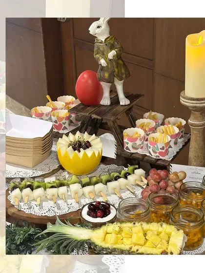 A unique grazing table for a kids' party, featuring fruit skewers, mini fries in decorative cups, and other child-friendly snacks arranged with whimsical decor like a Peter Rabbit figurine.