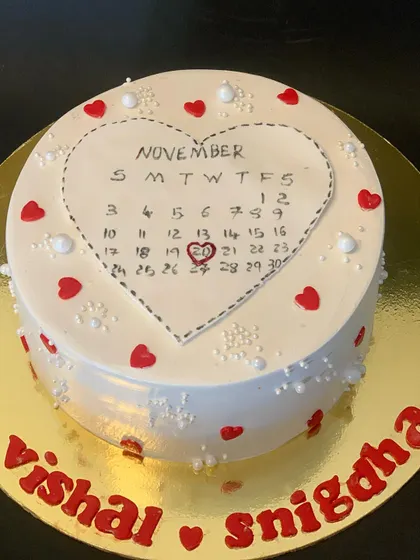 A unique anniversary cake featuring a calendar marking the special day. The design is simple and heartfelt, decorated with little red hearts.