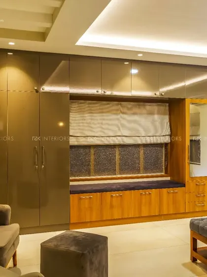 This bedroom showcases a custom-made wardrobe with a glossy finish and a built-in seating area by the window. The design cleverly combines storage with a cozy reading nook.