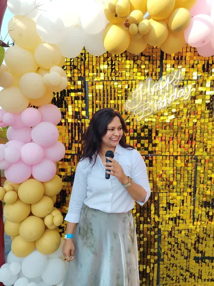 A happy moment captured in front of a festive birthday backdrop. As a birthday host, my goal is to reflect the joy of the occasion in every interaction.