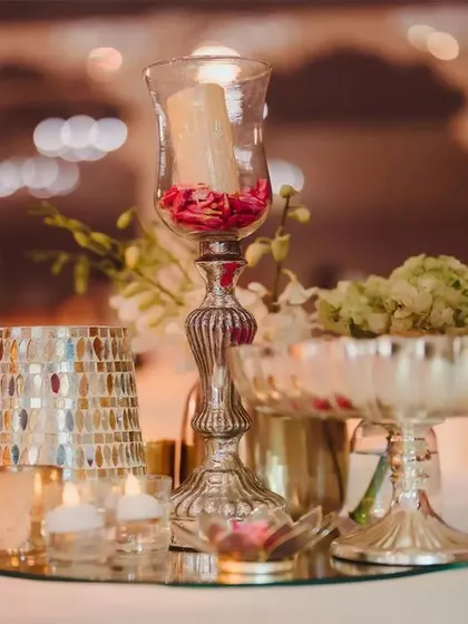 Detail is everything. This centerpiece combines mirrored mosaic vases, classic silver bowls, and tall glass candle holders to create a look of timeless elegance on each table.