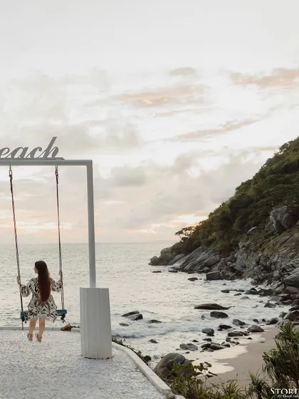A beautiful wide shot of the bride-to-be on a swing at Nui Beach, capturing the vastness of the ocean and the feeling of escape.