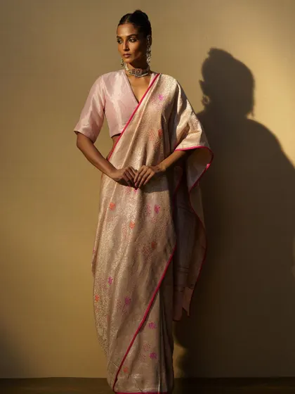 A light, airy handwoven saree with a pink border, paired with a matching blouse and a simple choker. This is perfect for a daytime event or as part of a trousseau.