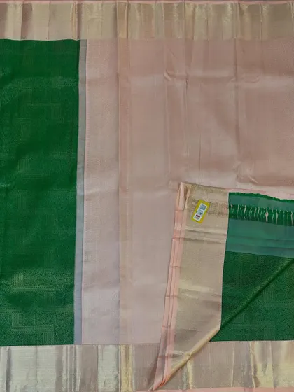 A flat-lay view of a classic pure Kanjivaram silk saree. This shows the beautiful contrast between the light peach body and the traditional green border, a timeless combination for any special occasion.
