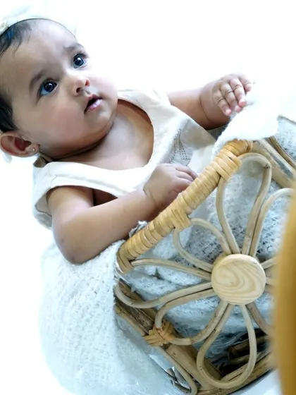 A baby looks up inquisitively from a cozy basket setup. We use different angles and perspectives to create a diverse gallery of images from a single baby photoshoot session.