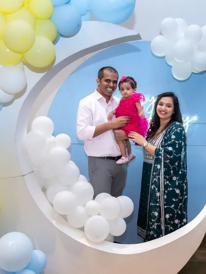 A family poses for a photo inside a moon-shaped prop at a whimsical first birthday party. We love using creative decor elements to make your family photos unique and fun.