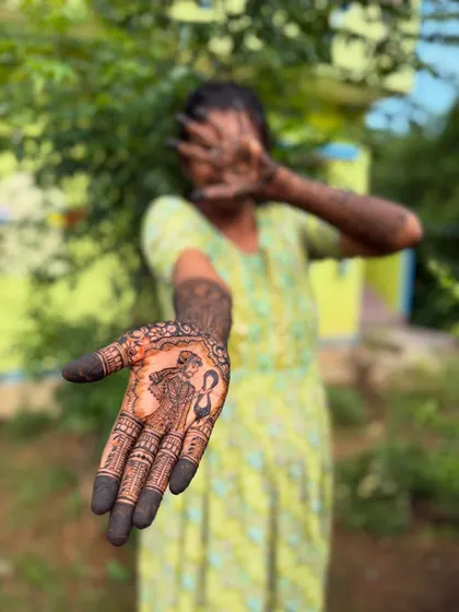 A creative shot focusing on the groom (dulha) portrait on the bride's palm. I enjoy drawing these detailed figures that add a personal narrative to the bridal mehendi.