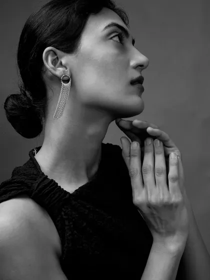 A contemplative profile shot. The soft light catches the details of her earring and the gentle curve of her hands, creating a moment of quiet grace.