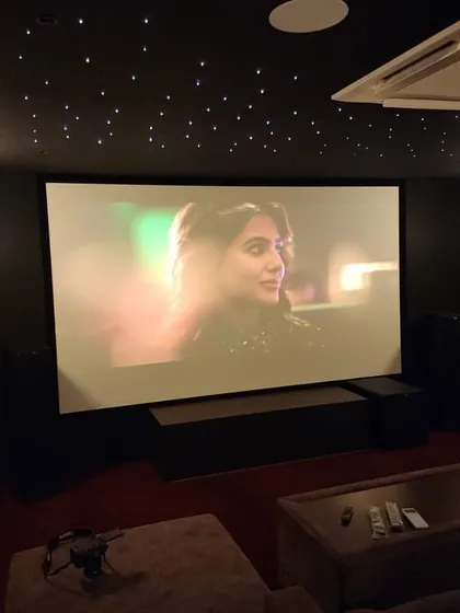 This luxury home cinema in Salem features a warm and inviting design with brown fabric recliners, a starlit ceiling, and soft wall sconce lighting.
