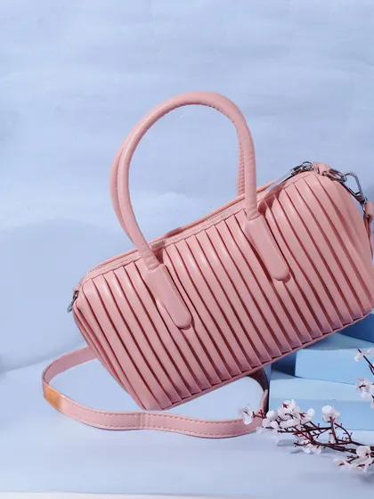 A playful and chic shot of a pink pleated handbag. The light blue background and floating composition give it a fun, summery, and fashionable vibe.