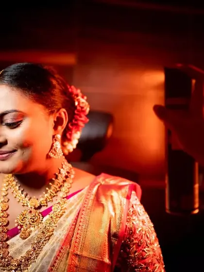A close-up of a makeup artist giving the final touches to a South Indian bride, highlighting the artistry and preparation involved.