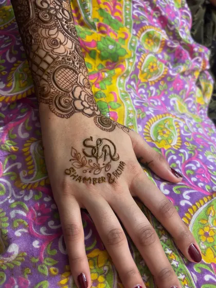 A simple yet elegant personalization on the palm, with the couple's initials and names. The rest of the arm can be filled with intricate patterns or left simple.