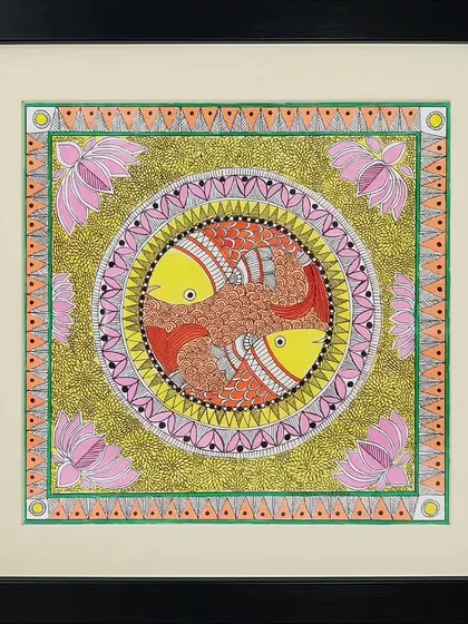 Two fish swim in a circle in this Madhubani painting by Neha Kumari. The piece is rich with color and texture, from the golden-green background to the pink lotus flowers in the corners.