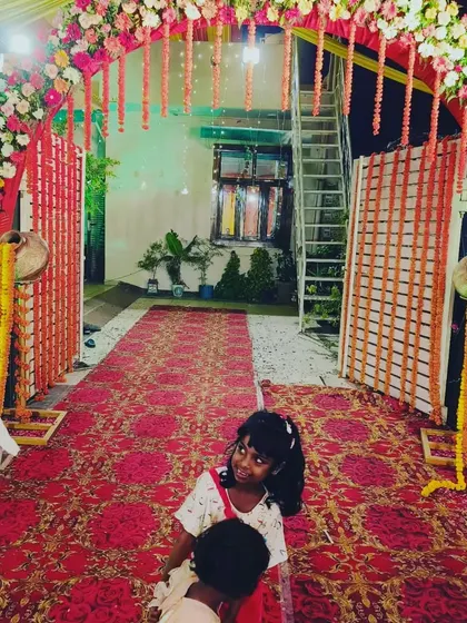 This is a floral entrance arch perfect for a home wedding or a smaller outdoor venue. The arch is decorated with mixed flowers and traditional earthen pots (matkas) with marigold strings, blending modern and traditional elements.