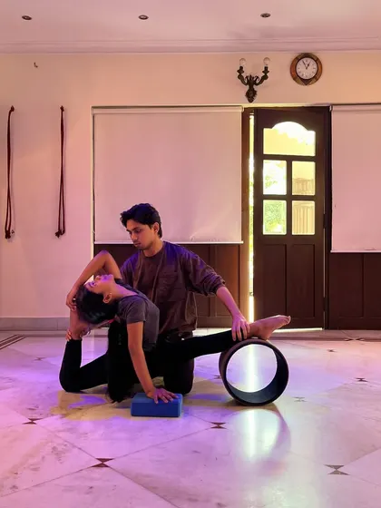 Using a yoga block for additional support while guiding a student into a deeper stretch.