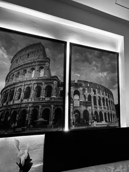 The large, black-and-white prints of the Colosseum above the bed are backlit, adding a dramatic and sophisticated touch to the room.