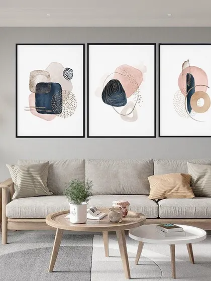 This triptych of framed prints features abstract compositions in shades of navy, pink, and beige. The mix of textures and shapes creates a sophisticated and modern gallery wall that is both calming and visually interesting.