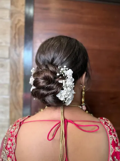 This fresh wedding bun is styled with delicate white flowers and baby's breath. It's a romantic and timeless choice for any bride on her wedding day.