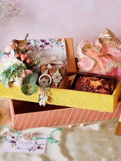 The Traditional Gota Tray Rakhi Hamper is perfect for a classic celebration. It includes a fudge brownie box, a walnut & chocolate tea cake, and NYC chunk cookies.