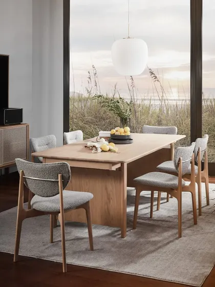 The Copenhagen extendable dining table, set against a picturesque window. Paired with bouclé fabric chairs, this setting embodies the collection's ethos of sparking meaningful conversations in an atmosphere of simple, modern elegance.