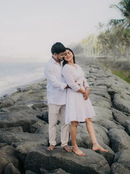 A romantic embrace on a rocky shore, capturing the couple's connection.