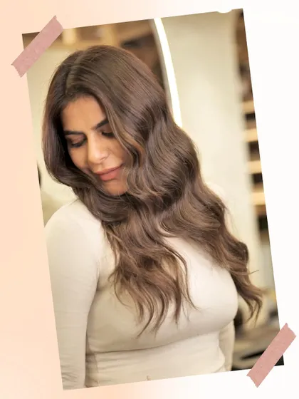 A portrait of a client with her new Iconic Brown hair color. The soft waves and rich tones create a look of effortless sophistication.