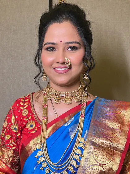 A wedding-ready bride in a blue and red saree. The makeup is flawless, with traditional jewelry completing the classic Maharashtrian look.