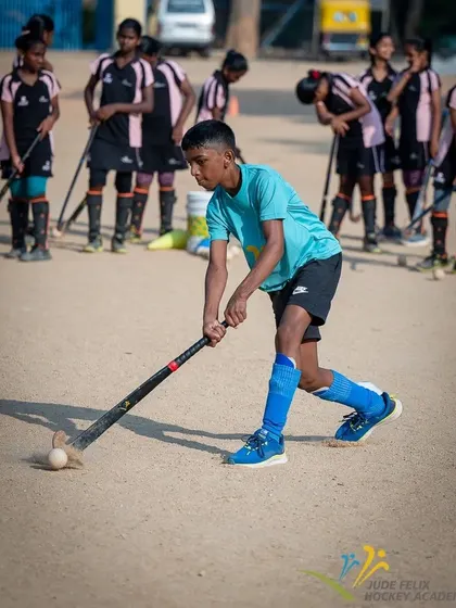 A player from our 2024 camp practices his dribbling, with his teammates looking on. The supportive environment helps everyone learn and grow together.