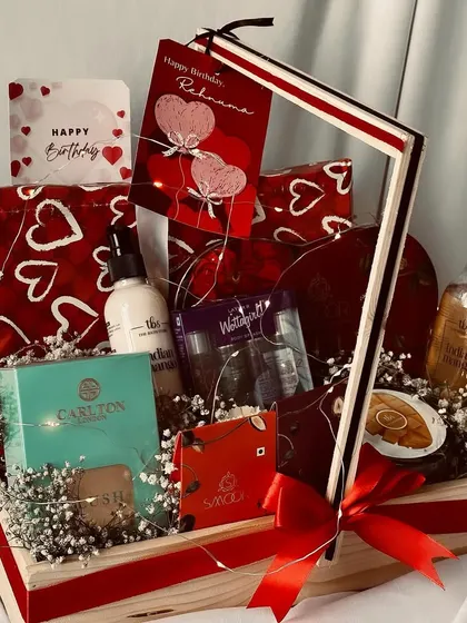A beautiful birthday hamper with a red and white heart theme, including skincare products, chocolates, and fairy lights for a magical touch.