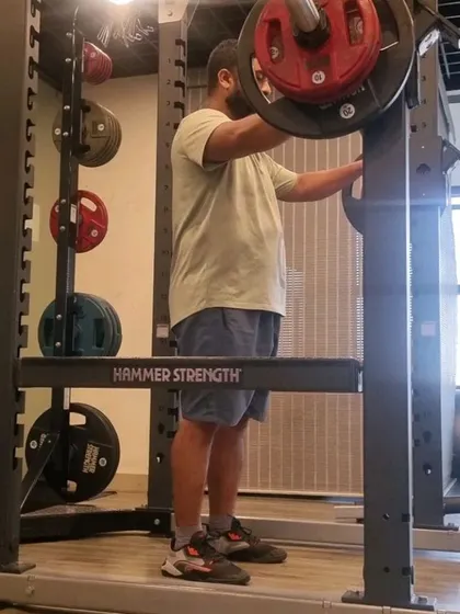 A client getting ready to squat inside a power rack, ensuring a safe environment for heavy lifting.
