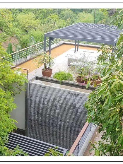 A relaxed, outdoor retreat corner of a home in Alibaug. This elevated deck with a pergola provides a private space to enjoy views of the surrounding forestry, demonstrating our focus on creating usable outdoor spaces.