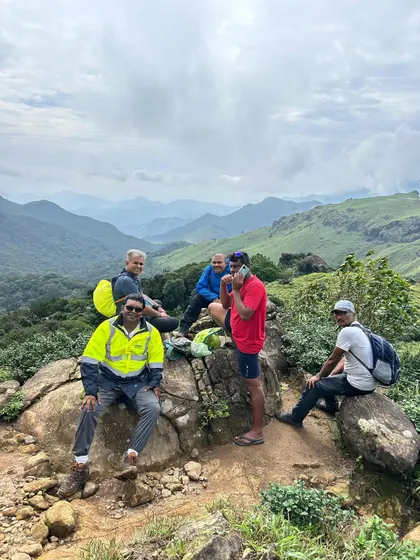 Taking a well-deserved break at a viewpoint on the Thadiyandamol trek. The panoramic view of the surrounding hills is the perfect reward.