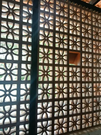 The view from inside looking through a completed jali wall. It beautifully frames the outdoor greenery while providing privacy, demonstrating its dual function as both a window and a screen.