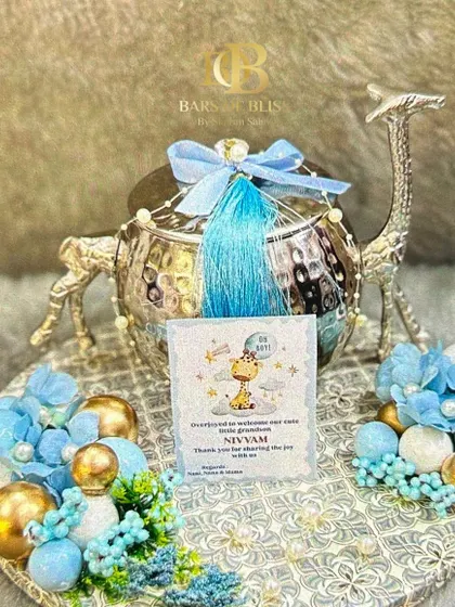 A unique and luxurious baby announcement hamper. This one features a silver-plated, camel-shaped container on a decorated tray, with a personalized card announcing the baby's arrival.