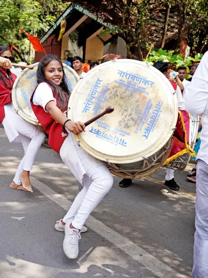 The power and rhythm of the dhol-tasha pathak. I use a dynamic angle to photograph the performers, conveying the sheer energy of their movements during the street festival.
