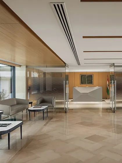 The main reception lounge of The Layered Office, featuring polished marble floors and wood-paneled walls, looks out onto the central courtyard with its grand sculptures.