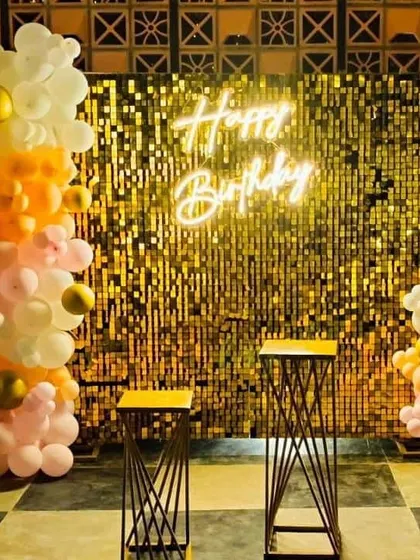 A popular choice for birthdays and parties, this photo booth combines a shimmering gold sequin wall with a custom "Happy Birthday" neon sign. The organic balloon garland in pastel and gold tones adds a modern, celebratory feel.