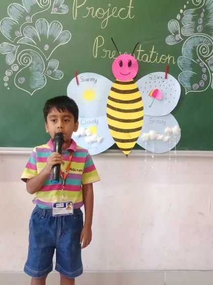 A student explains different weather types with his handmade butterfly chart, a creative approach to learning about meteorology.