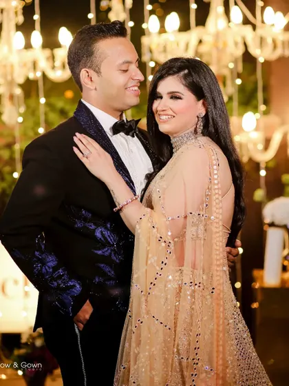 A glamorous portrait of the couple at their engagement party. They are posed against a backdrop of sparkling chandeliers, looking happy and in love.