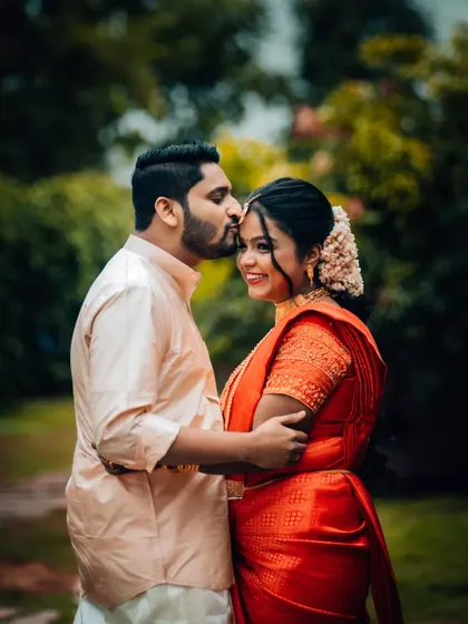 A groom's affectionate kiss on his bride's forehead, a timeless expression of love captured after their wedding ceremony.