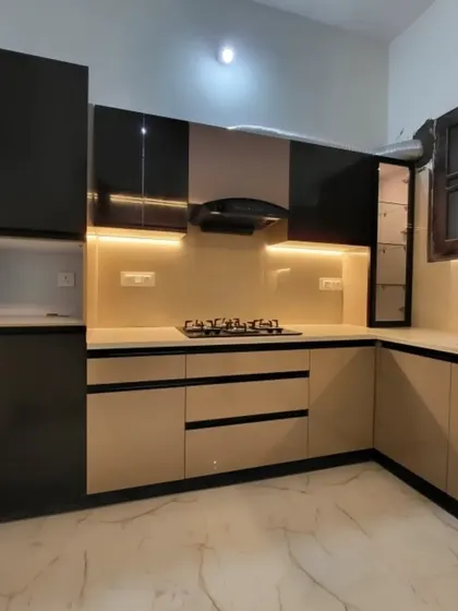 A sleek kitchen with high-gloss beige and black cabinets. Under-cabinet lighting provides excellent task illumination on the countertop.