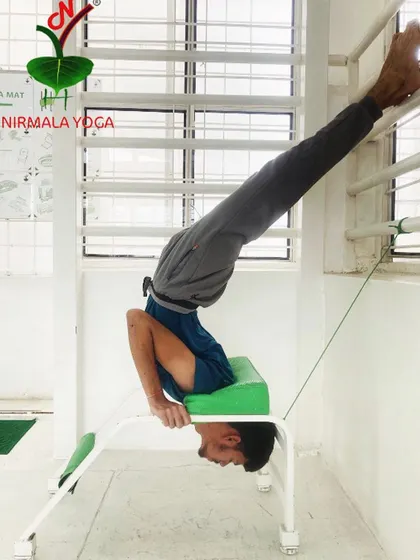 This is a variation of Vrischikasana (Scorpion Pose) using a headstand bench and the wall. This combination of props makes this very advanced pose comfortable and accessible, allowing for a deep and safe backbend.